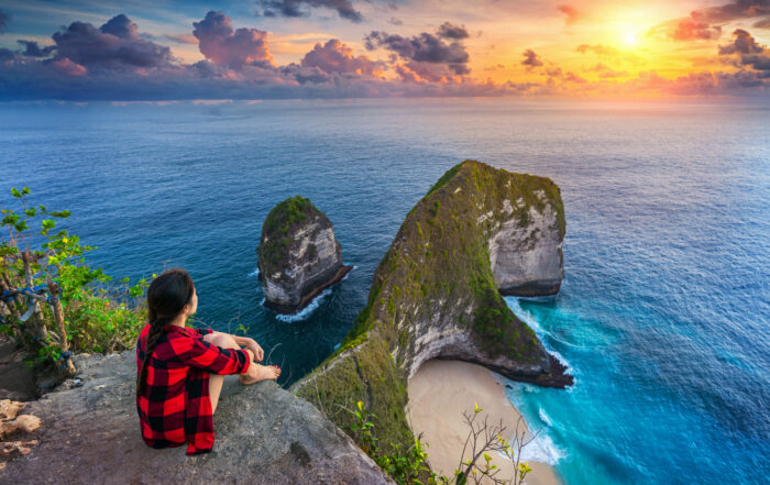 Woman sitting on cliff and looking at sunset at Kelingking Beach  Mitra IT | Your Trusted & Reliable Software Solutions