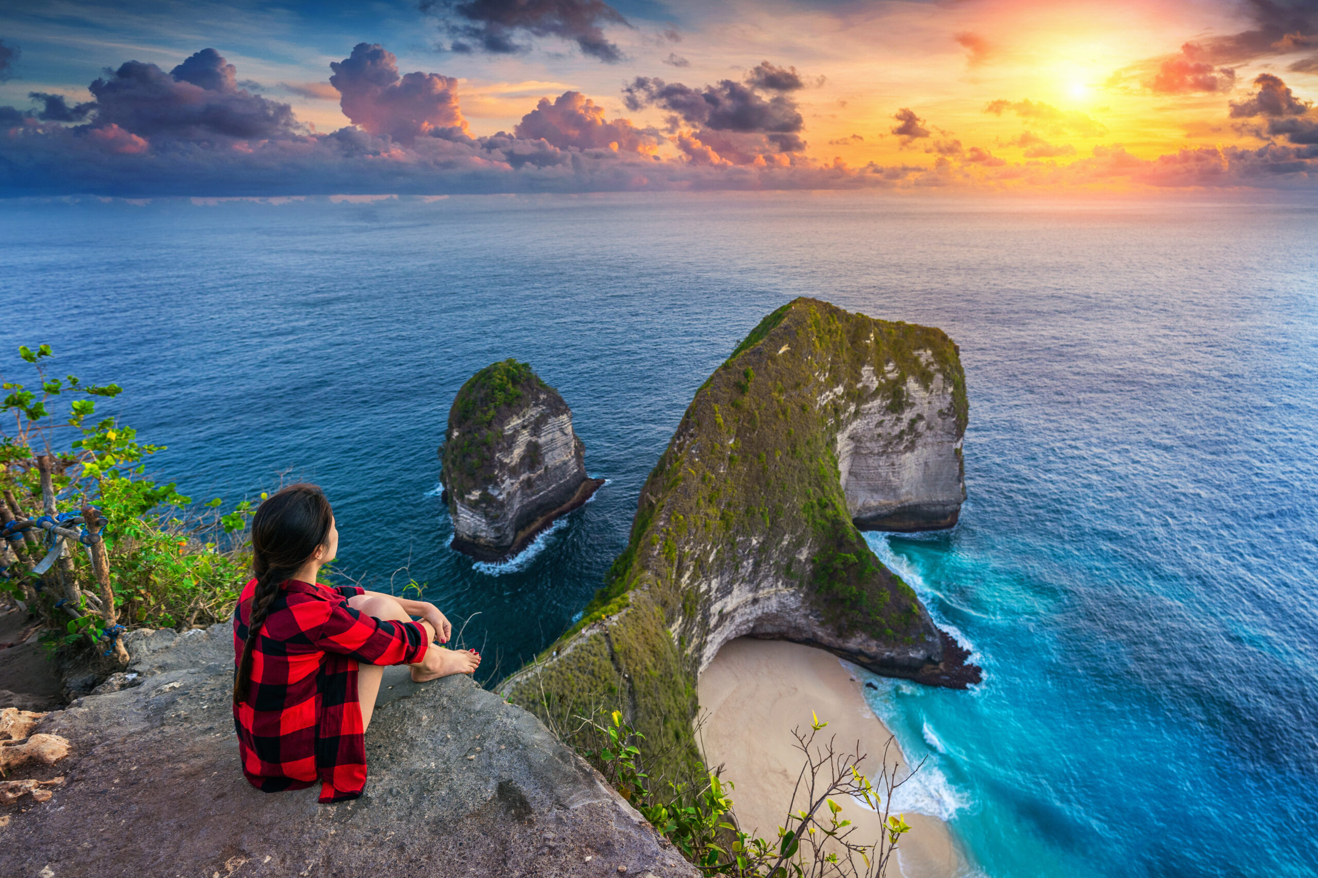 Woman sitting on cliff and looking at sunset at Kelingking Beach Mitra IT | Your Trusted & Reliable Software Solutions